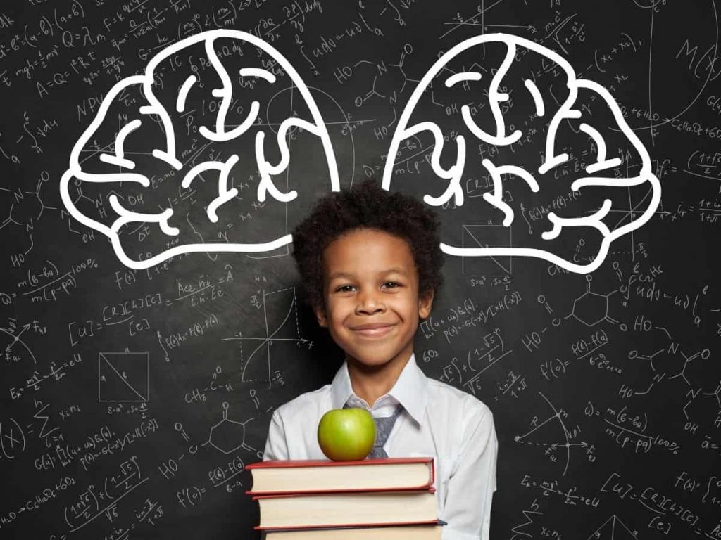 smiling brainiac kid standing in front of chalkboard