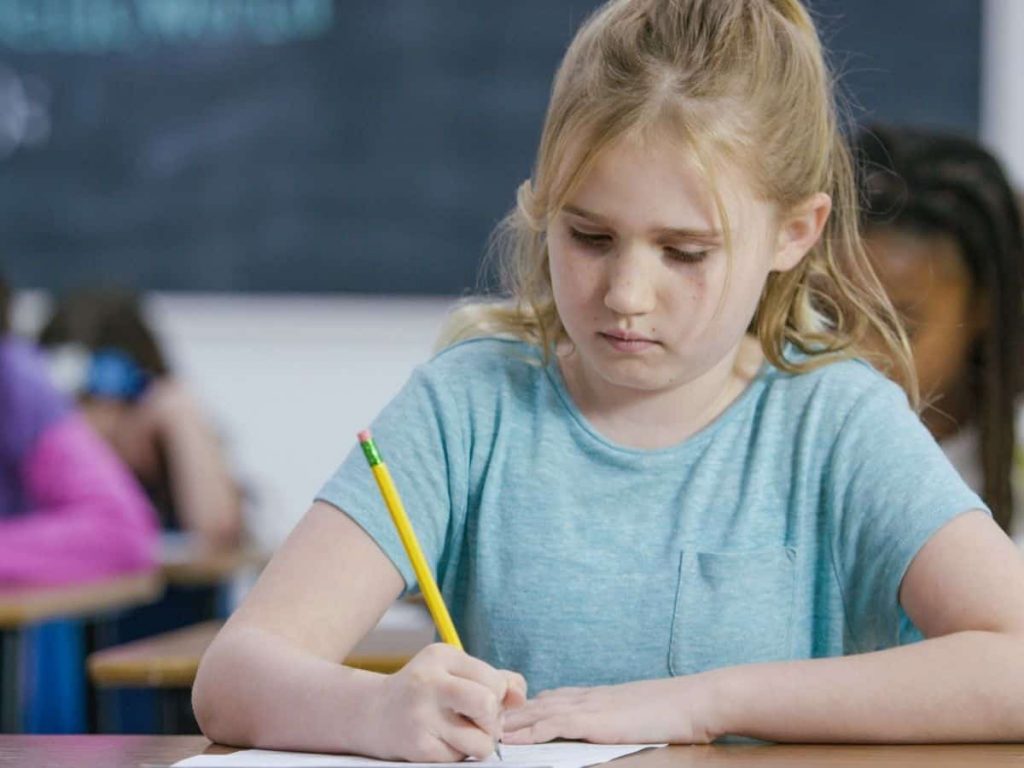 little blonde girl working hard in class
